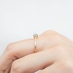 a woman's hand holding an engagement ring with a diamond in the middle, against a white background