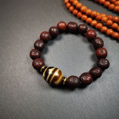 This unique Dalo Dzi bracelet combines the mysterious and unique qualities of the tiger tooth dalo dzi and 15 old bodhi seed beads,giving it a distinct feel.It is brown in color and has a circumference of approximately 7 inches, suitable for most wrist sizes.This bracelet can be worn not only as a fashionable accessory but also holds cultural and religious significance.Dzi beads are precious jewelry from Tibetan culture which are believed to possess the power of bringing good fortune to the owne Traditional Hand Wrapped Brown Bracelet, Hand Wrapped Brown Beaded Bracelets For Meditation, Handmade Brown Beaded Bracelets For Ceremonial Use, Handmade Brown Beaded Bracelets For Rituals, Spiritual Brown Beaded Bracelets, Spiritual Brown Bracelet For Rituals, Traditional Brown Beaded Bracelet With Polished Beads, Brown Beaded Bracelets With 8mm Beads For Meditation, Earthy Brown Beaded Bracelets For Meditation