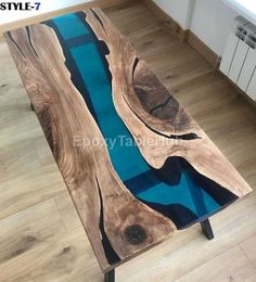 a coffee table made out of wood and blue glass in the center, on top of a wooden floor