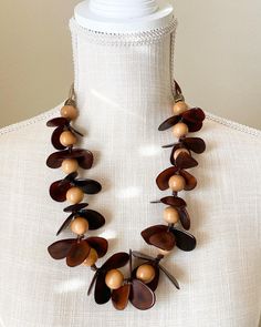 A striking necklace inspired by nature! The tagua petals and bombona seeds are arranged in such a way that they look like real orchids with their small buttons. Pair this wonderful necklace with a solid top or a simple cocktail dress. Thanks to the natural characteristics you can be sure yours is unique. Tagua, also called the vegetable ivory is the seed of a palm tree that grows in the tropical rainforests of several South American countries including Colombia and Ecuador. Handmade in the USA. Mocha Fudge, Simple Cocktail Dress, Simple Cocktail, Orchid Necklace, Seed Necklace, Tagua Jewelry, South American Countries, Radiant Orchid, Tropical Rainforest