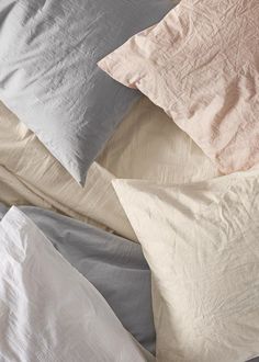 four pillows are laying on top of each other in different colors and sizes, along with one another