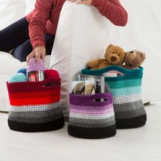 a woman sitting on a couch with two crocheted baskets