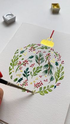 someone is painting a christmas ornament with watercolors