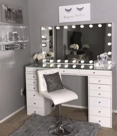 a white chair sitting in front of a desk with a mirror and lights on it