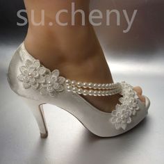 a woman's white high heeled shoes with pearls