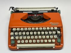 an orange typewriter sitting on top of a white table