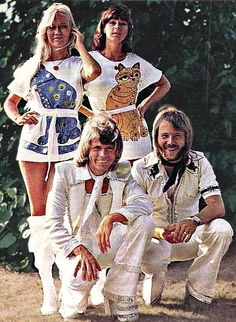 the bee gees are posing for a photo in front of some trees and bushes