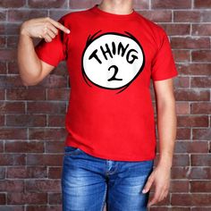 a man wearing a red thing 2 t - shirt pointing to his left side with the number two on it