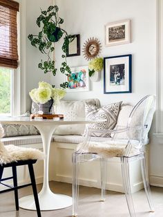 a living room filled with furniture and flowers on the wall next to a white table