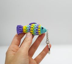 a hand holding a small toy fish on a chain