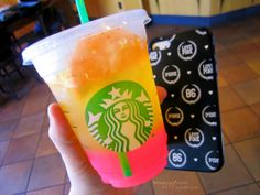 a hand holding up a starbucks drink in front of a tiled floor