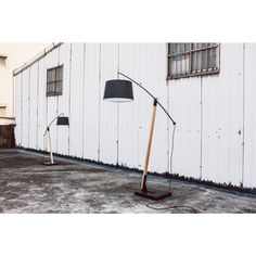 two floor lamps sitting next to each other on the ground in front of a white building