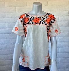 Such a cute embroidered top, with great boho style! It's made from a natural ivory cotton gauze fabric with a crinkly texture and embroidered in shades of orange and brown with some small red accents. It's finished with two cute little pockets on the bottom front. Unlined. No labels. Measurements: no size tag; this is approx a modern XS/S. The fabric has a bit of give due to the crinkly texture - at rest the bust measures 34". It's 25" long from shoulder to bottom and the shoulders are 18" across the back (measured from edge to edge from the embroidered border). Material: no tag; this feels like cotton. The embroidery thread is yarn-like and probably an acrylic. Condition: freshly hand laundered and in excellent vintage condition - there's one very faint stain on the front (it might actual Spring Bohemian Crew Neck Blouse, Bohemian Crew Neck Top With Geometric Embroidery, Bohemian Tops With Geometric Embroidery And Crew Neck, Vintage Beige Festival Tops, Orange Embroidered Tops For Summer, Bohemian Crew Neck Blouse With Floral Embroidery, Orange Floral Embroidery Short Sleeve Tops, Orange Floral Embroidered Short Sleeve Tops, Orange Short Sleeve Tops With Floral Embroidery