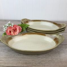 two white and gold serving dishes with pink flower on each one, sitting on a wooden table