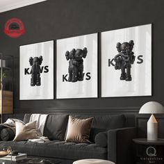 a living room filled with black furniture and pictures on the wall above it's coffee table