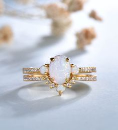 an opal and diamond ring is shown on a white surface with flowers in the background