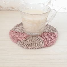 a glass cup sitting on top of a knitted coaster