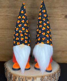 two orange and white gnomes sitting on top of a tree stump next to each other