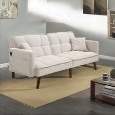 a white couch sitting on top of a rug in a living room next to a coffee table