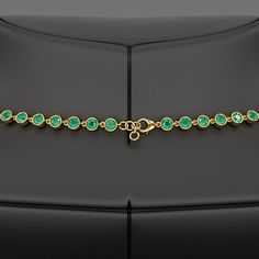 a gold bracelet with green stones on it