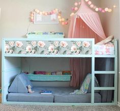 a child's bedroom with a bunk bed and pink curtains on the window sill