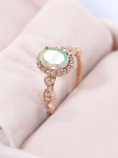 an opal and diamond ring sits on a white cloth