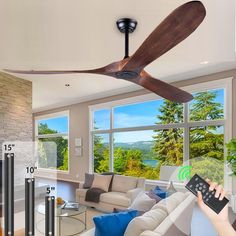 a person holding a remote control in front of a living room with a ceiling fan