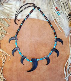 Grizzly Bear Claw Necklace handmade with imitation bear claws made from resin.  Necklace includes hairpipe beads, turquoise and silver plated beads with an adjustable deerskin tie in back.  Include six 2" faux bear claws and one 3" faux bear claw.  Great for SASS shooting, costumes, Native American Indian PowWows and more. Choose Brown Rosewood,  BrownAmber Horn, Black Horn or Buffalo Bone Hairpipe Beads.  If you would like a custom one of these made differently, just message me. See my other listings for Hat Bands, Horse Hair Keepsakes, Boot Bracelets, Earrings, Chokers, Hair Feather Clips, Bolo Ties, Dreamcatchers, Glasses and Mask Holders, Necklaces and more. Tami Blue Eyes Designs www.BlueEyesDesignsHB.com BlueEyesDesignsHB@gmail.com Tulsa King, Hunting Crafts, Bear Claw Necklace, Hair Keepsake, Necklace Drawing, Boot Bracelet, Antler Necklace, Claw Necklace, Bear Claw