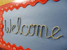 the word welcome is written in rope on a blue board with red and white border