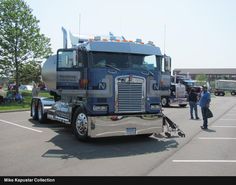 a large semi truck parked in a parking lot with people standing around and looking at it