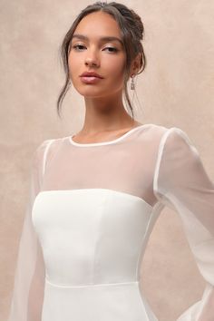 a woman wearing a white dress with sheer sleeves