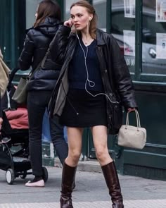 a woman is walking down the street talking on her cell phone and listening to music