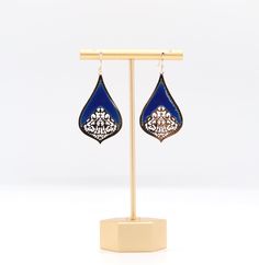 a pair of blue and white earrings on a stand