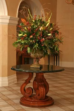 a vase with flowers on top of a glass table in a room that has tile flooring