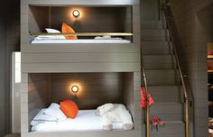 two bunk beds with white sheets and orange pillows on the bottom, one has an orange pillow