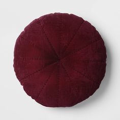 a red round cushion sitting on top of a white wall