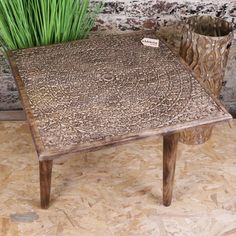 a wooden table sitting on top of a hard wood floor next to a potted plant