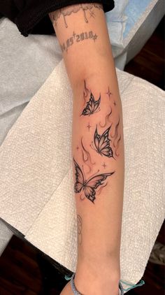 a woman's arm with tattoos on it and two butterflies in the middle of her arm