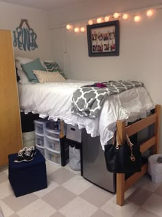 a dorm room with a bed, desk and storage bins