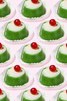 there are many green and orange desserts on the tray with cherries in them