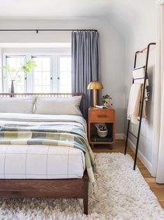 a bed sitting in a bedroom next to a window with curtains on the windowsill