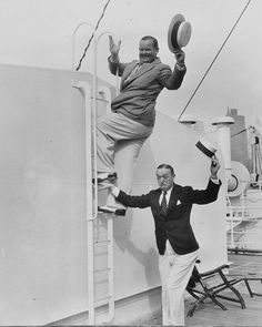 two men are standing on the deck of a ship and one is holding onto another man's hat