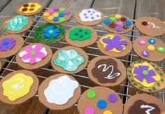 some cupcakes that are sitting on a cooling rack with icing and buttons