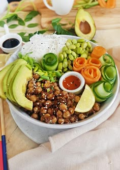 a white bowl filled with vegetables and meats next to chopsticks on a table