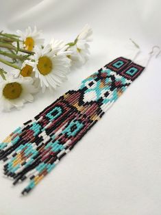 some daisies are sitting next to a beaded bracelet with an image of a woman's face on it