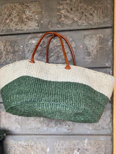 a green and white bag hanging from the side of a wall next to a shoe