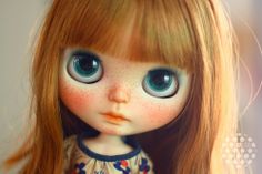 a close up of a doll with freckles on it's face and blue eyes