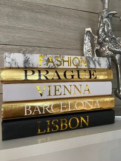 a stack of five books sitting on top of a white shelf next to a statue