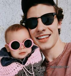 a man holding a baby wearing sunglasses