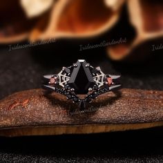 a black diamond ring sitting on top of a piece of wood next to an orange flower